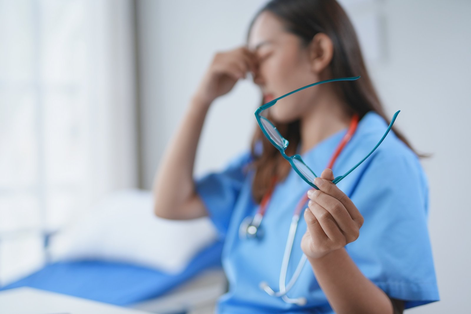 Young nurse having a moment of respite in a hospital room, massaging her eyes
